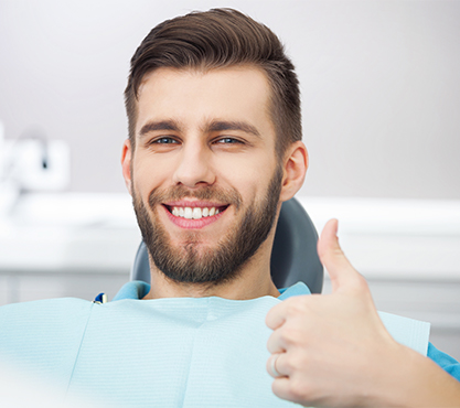 Man in dental chair giving thumbs up