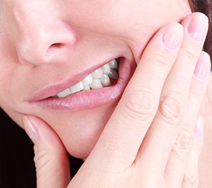 Closeup of grimacing person holding jaw