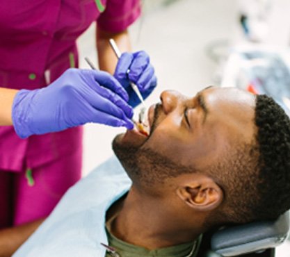 Man smiling while dental assistant looks at his teeth