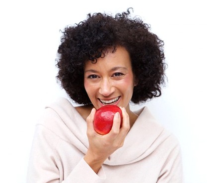 smiling woman biting into a red apple