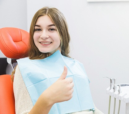 Female dental patient smiling and giving a thumbs up