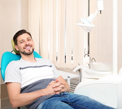 Male in dental chair laying back and smiling