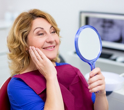 dental patient admiring her new smile in a mirror