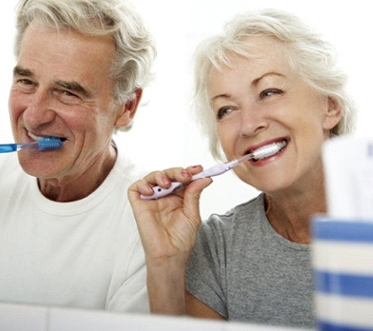 senior man and woman brushing their teeth