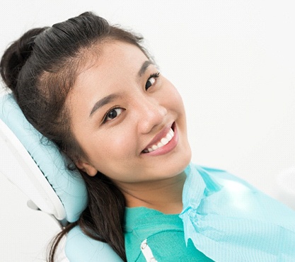 Woman leaning back in dental chair smiling after teeth whitening in Richardson, TX
