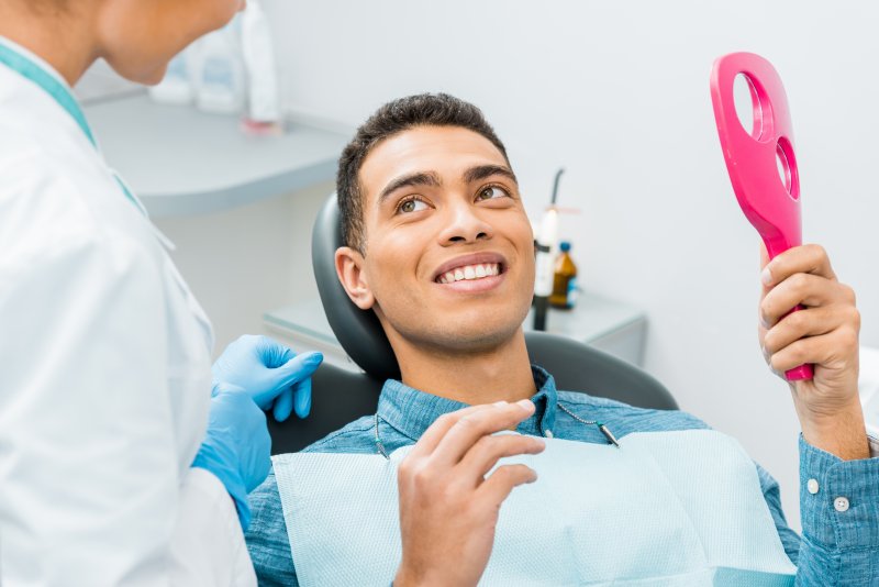 young man smiling sitting in dentist chair after dental visit