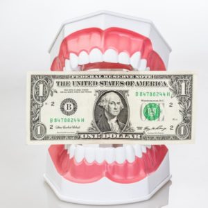 Teeth sitting on a table holding a $1 bill 