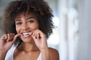 flossing woman smiling because she knows why flossing is important 